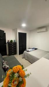 ein Zimmer mit zwei Betten und einem Tisch mit Blumen in der Unterkunft Torreón Jardin apartment near IMSS clinics 16 and 71 in Torreón