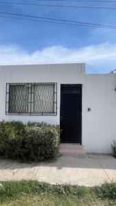 ein weißes Gebäude mit einer schwarzen Tür und zwei Fenstern in der Unterkunft Torreón Jardin apartment near IMSS clinics 16 and 71 in Torreón + 12 Fotos