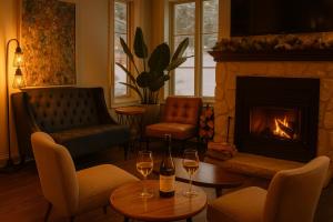 a living room with a fireplace and two glasses of wine at Le 900 Tremblant Inn Café and Bistro in Mont-Tremblant