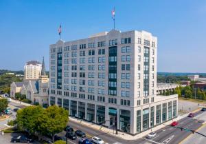 un grand bâtiment blanc avec des voitures dans une rue de la ville dans l'établissement Landing Apartments - Spartanburg, à Spartanburg