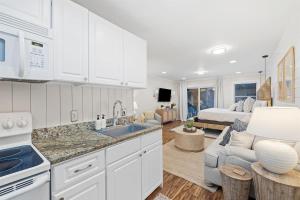 a kitchen with white cabinets and a living room with a bed at Grandy 30A in Inlet Beach
