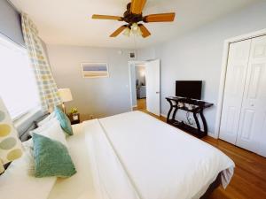 a bedroom with a white bed and a ceiling fan at Great Escape Apartments By Lowkl in Fort Lauderdale