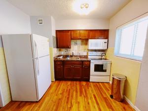 a kitchen with a white refrigerator and wooden floors at Great Escape Apartments By Lowkl in Fort Lauderdale