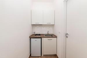 a small kitchen with white cabinets and a sink at LORY'S HOUSE in Porto Cesareo