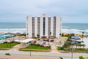 a large white building with a parking lot and the ocean at Van Lee 1003 - Oceanview Beach Condo in Ormond Beach