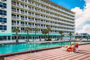 a man sitting in a lawn chair in front of a hotel at Daytona Beach in Daytona Beach