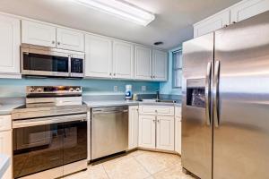 a kitchen with white cabinets and stainless steel appliances at Van Lee 1003 - Oceanview Beach Condo in Ormond Beach