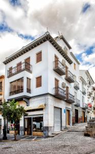 a white building with balconies on a street at Monteftur in Montefrío