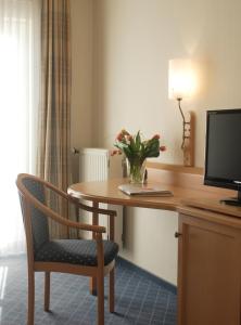 einen Schreibtisch mit einer Vase aus Blumen auf einem Tisch mit einem Stuhl in der Unterkunft Hotel Zur Eich in Wermelskirchen