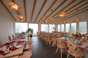 een restaurant met houten tafels en stoelen en ramen bij Hotel Waldschlösschen und Spezialitätenrestaurant in Oberhof
