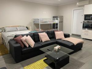 een woonkamer met een zwarte bank en een bed bij Serene Guest House in Callala Beach