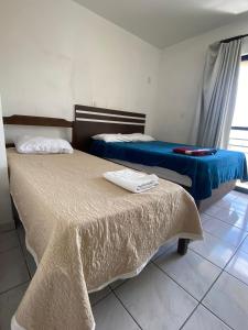 two beds sitting in a room with a window at Hotel Menegatti in Pato Branco