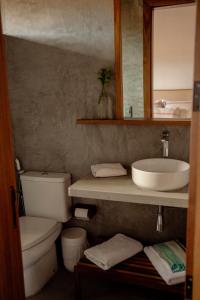 een badkamer met een wastafel, een toilet en een spiegel bij Casa Teçá in Guriú