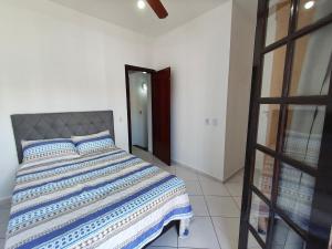 een slaapkamer met een bed met een blauw en wit dekbed bij Casa em condomínio no centro de Bertioga in Bertioga