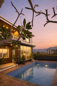 a house with a swimming pool in front of a house at ll EMPYREAN STAYS ll G0DFATHER VILLA ll MASTERPIECE ll 4BHK ll AC ll LARGEST POOL ll in Lonavala