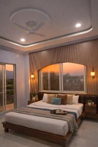 a bedroom with a large bed with a large window at ll EMPYREAN STAYS ll G0DFATHER VILLA ll MASTERPIECE ll 4BHK ll AC ll LARGEST POOL ll in Lonavala