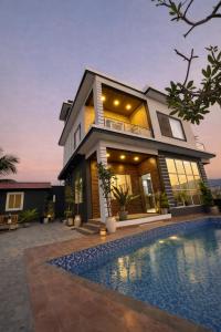 a house with a swimming pool in front of it at ll EMPYREAN STAYS ll G0DFATHER VILLA ll MASTERPIECE ll 4BHK ll AC ll LARGEST POOL ll in Lonavala