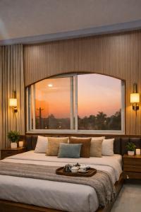 a bedroom with a large bed with a large window at ll EMPYREAN STAYS ll G0DFATHER VILLA ll MASTERPIECE ll 4BHK ll AC ll LARGEST POOL ll in Lonavala