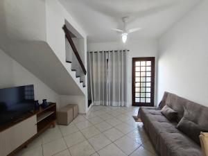 een woonkamer met een bank en een televisie bij Casa em condomínio no centro de Bertioga in Bertioga