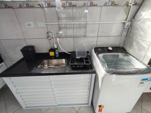 een kleine keuken met een spoelbak en een aanrechtblad bij Casa em condomínio no centro de Bertioga in Bertioga +61 foto's