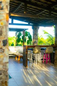 a patio with two chairs and a bar with palm trees at Casa Tavarua na Taíba in Taíba