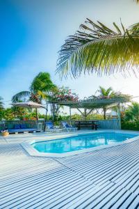 a swimming pool with a table and chairs and palm trees at Casa Tavarua na Taíba in Taíba