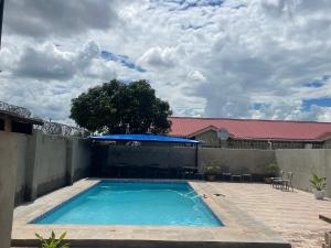 a swimming pool in a backyard with a fence at Cadami apartments in Mazabuka