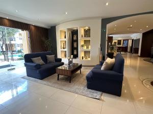 チワワにあるBest Western Plus Chihuahua Aeropuertoのリビングルーム(青いソファ2台、コーヒーテーブル付)