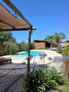 una piscina in un cortile con fiori viola di Cabañas Punta Arena a San Pedro