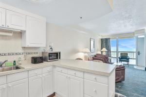 a kitchen with white cabinets and a living room at Daytona Beach Resort 532-White Turtle in Daytona Beach