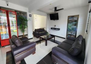 a living room with leather couches and a tv at Hotel Jardín Cancún in Cancún