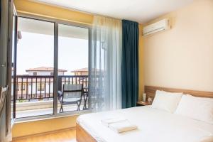 ein Schlafzimmer mit Bett und Balkon in der Unterkunft Harmony Hills Tomovi Casa 16 in Rogachevo + 13 Fotos