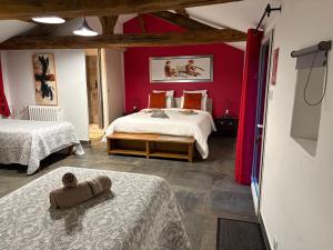 レ・ゼペスにあるAu Petit Bignonのベッドが2つあり、壁が赤い寝室