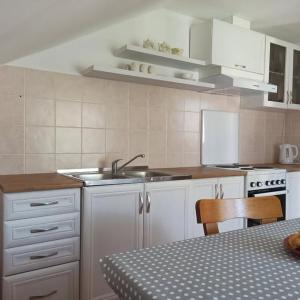 a kitchen with white cabinets and a sink and a table at Apartmani Brkan in Donja Lastva