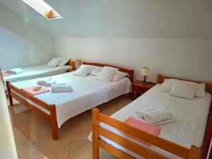 two beds in a room with two tables and a bedsenalsenalsenalsenalsenal at Apartmani Brkan in Donja Lastva