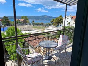 a balcony with a table and chairs and a view of the water at Apartmani Brkan in Donja Lastva