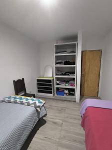 een slaapkamer met een bed en een plank met kleding bij Abadejo in Pinamar