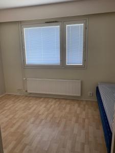 a bedroom with two large windows and a wooden floor at Loft house Karihaara in Kemi