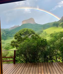un arcobaleno sopra una montagna con un ponte di legno di Casa Baú’au Vista Única Conforto em Familia a São Bento do Sapucaí