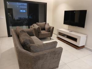 ein Wohnzimmer mit zwei Sofas und einem Flachbildfernseher in der Unterkunft Residence Helice in Kinshasa