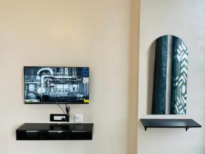 een televisie aan de muur met een zwarte plank bij BV Residency in Pondicherry