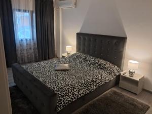 a bedroom with a bed with a black and white comforter at Apartament NECTARIA in Băile Herculane