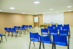 Zimmer mit blauen Stühlen, einem Tisch und einem Bildschirm in der Unterkunft Caruaru Pallace Hotel in Caruaru