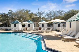 a swimming pool with lounge chairs and umbrellas at Sadie's Cottage in Rosemary Beach