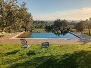 two chairs sitting in the grass next to a swimming pool at Vigna Luisa Resort - Near Rome in Genzano di Roma