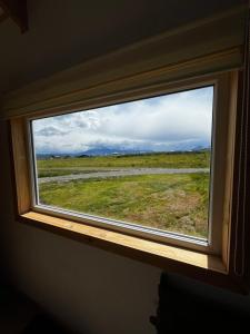 - une fenêtre dans une chambre avec vue sur un champ dans l'établissement Tiny House Camino 3, à Puerto Natales