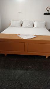 ein Bett mit weißen Laken und Kissen in der Unterkunft Rainbow Guest House in Mahabalipuram