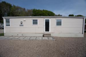 une caravane blanche avec une porte sur un terrain en gravier dans l'établissement No16 Caravan, home from home, à Angus