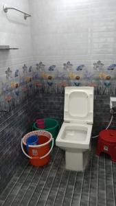 een badkamer met een toilet en emmers erin bij Rainbow Guest House in Mahabalipuram