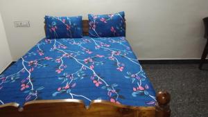 ein Bett mit einer blauen Tagesdecke mit Kirschen darauf in der Unterkunft Rainbow Guest House in Mahabalipuram
